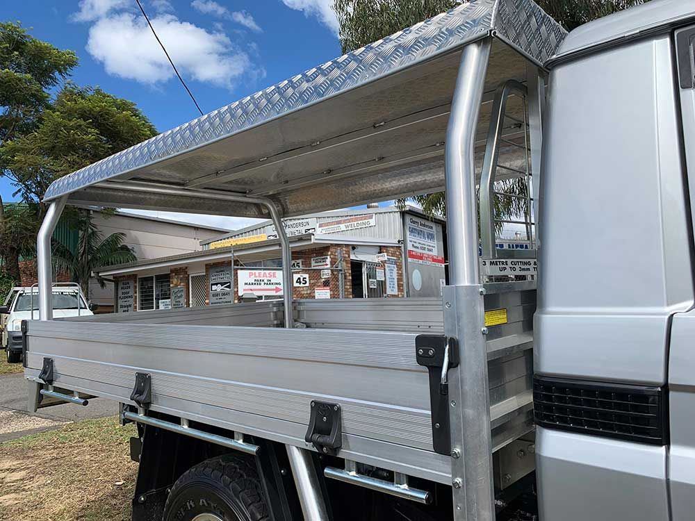 A Silver Truck With a Ladder on the Back is Parked in a Field — Clarry Anderson Sheet Metal Pty Ltd in Port Macquarie, NSW