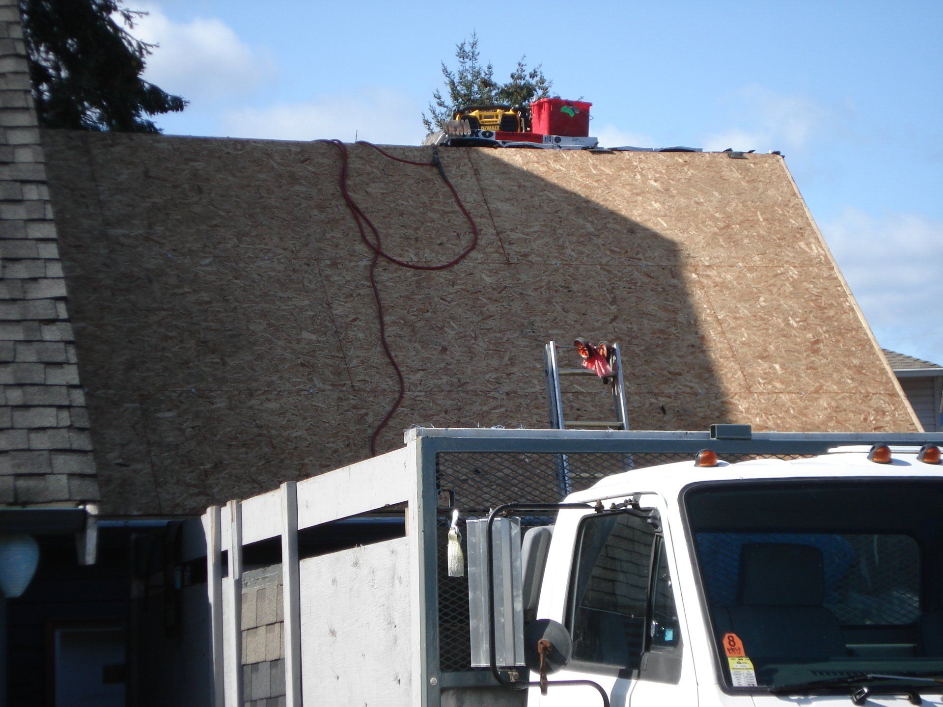 A white truck is parked in front of a roof under construction