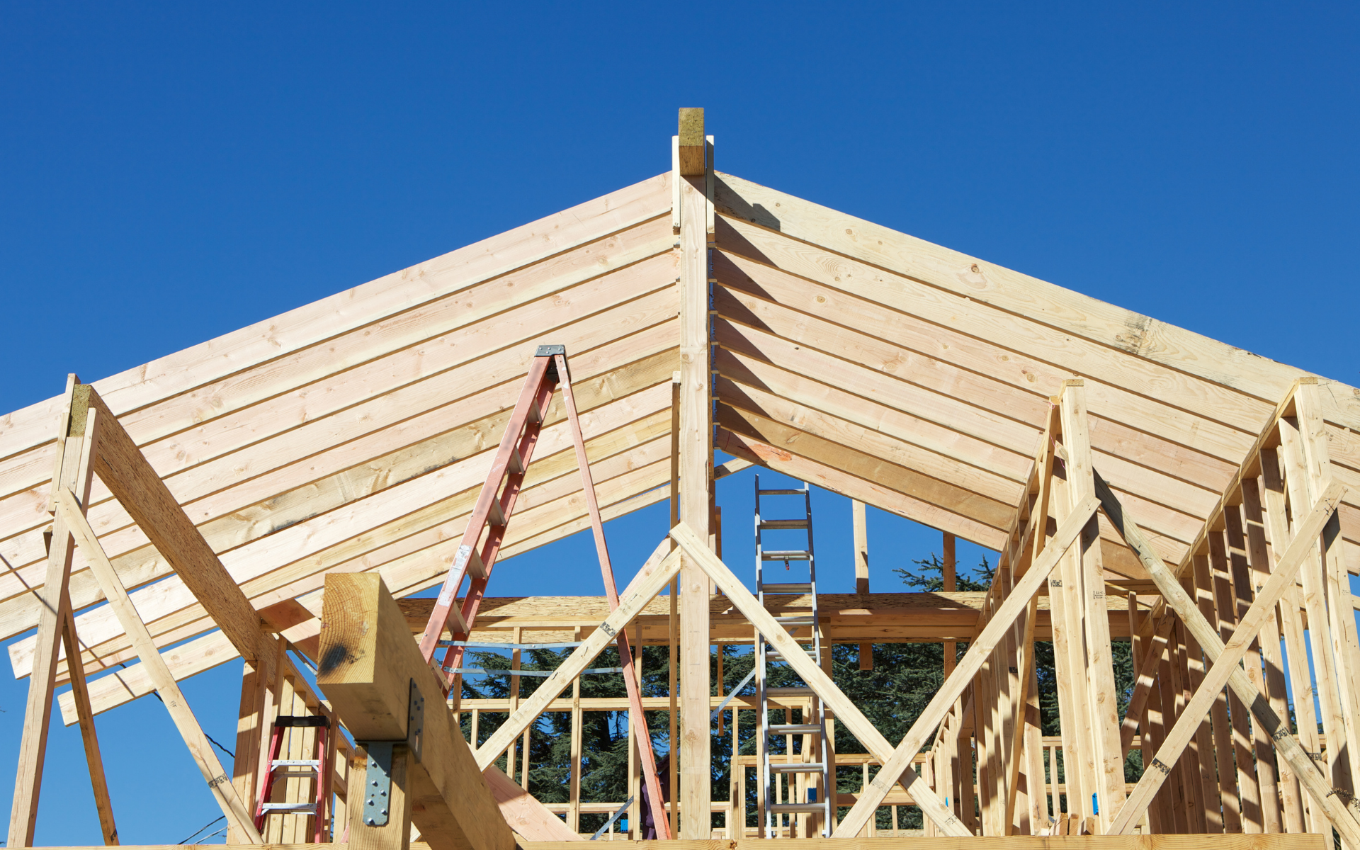 A wooden structure is being built with a blue sky in the background.