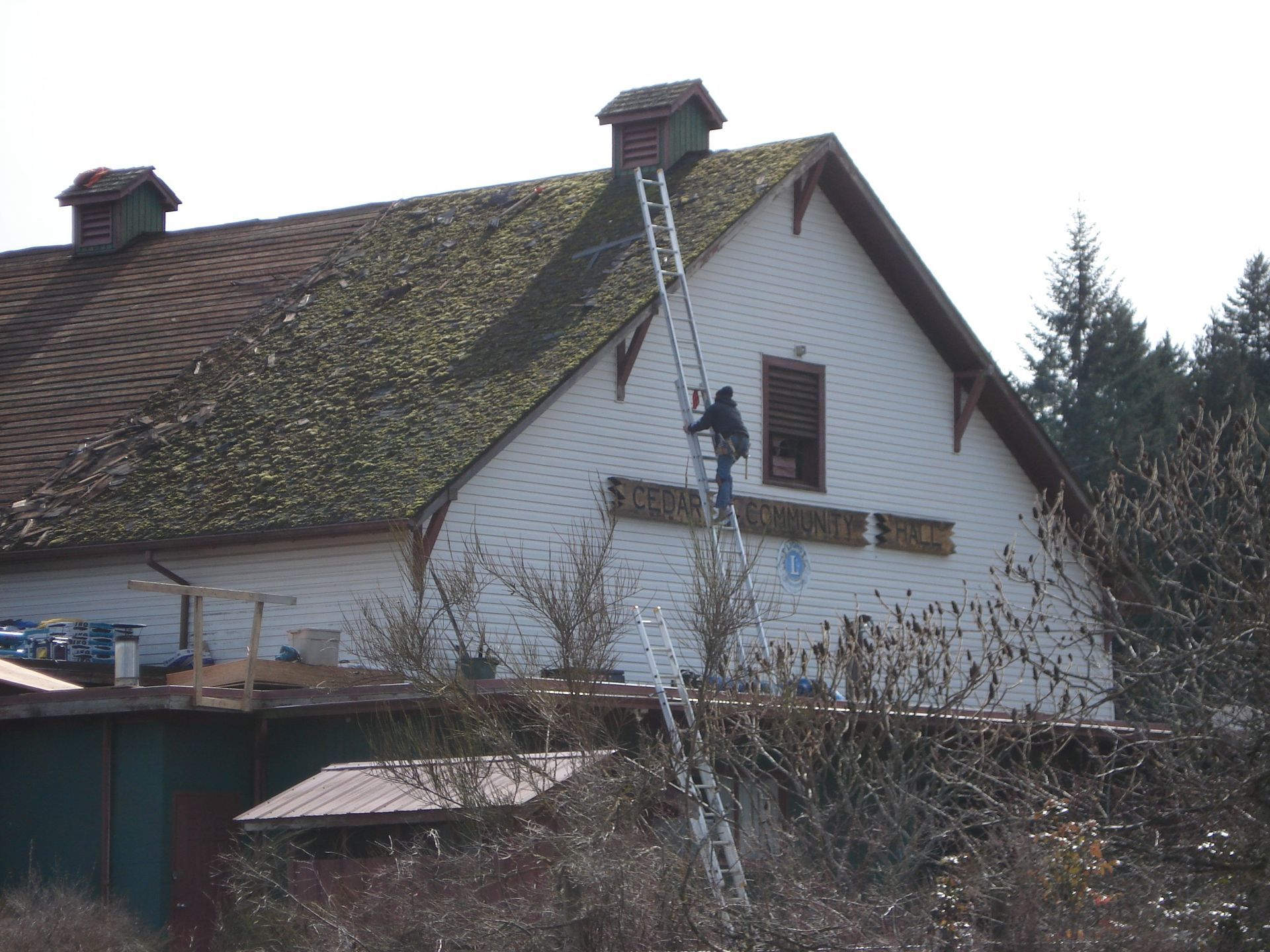 A man is standing on a ladder on the side of a house