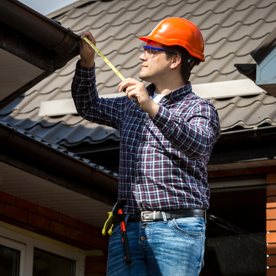 A man measuring a gutter with a tape measure