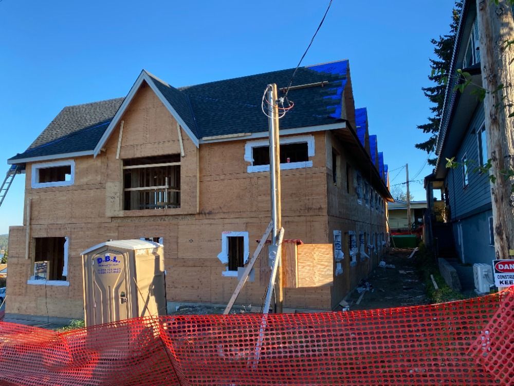 A house under construction with a portable toilet in front of it