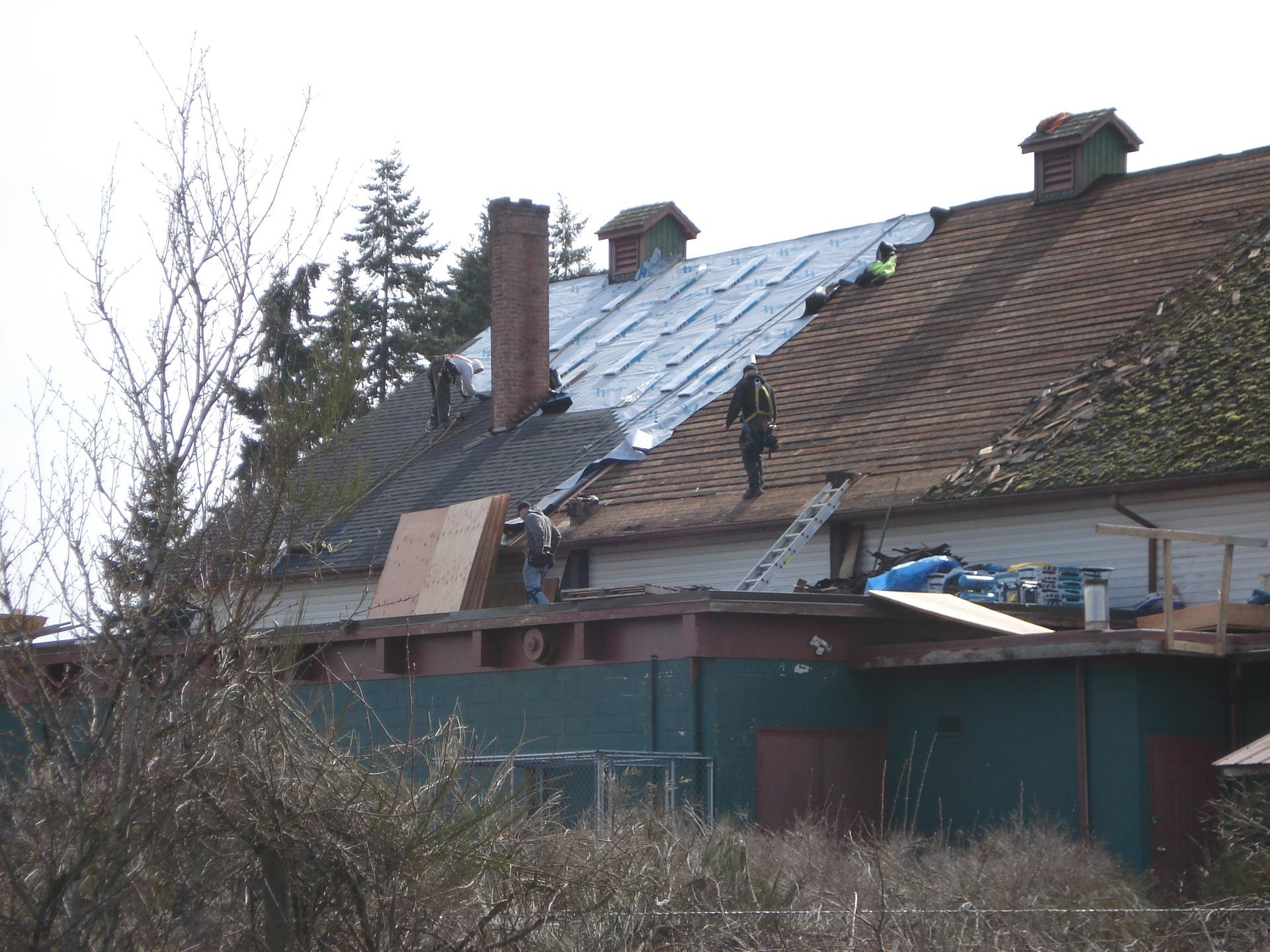 A group of people are working on the roof of a house