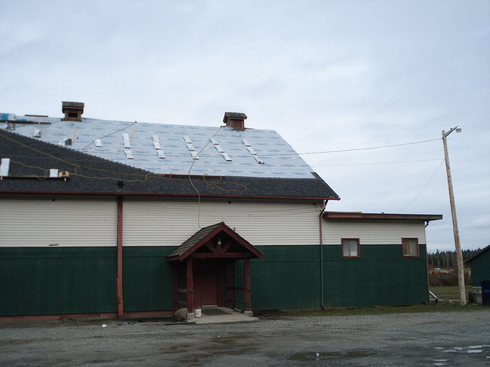 A green and white building with a roof that has shingles on it