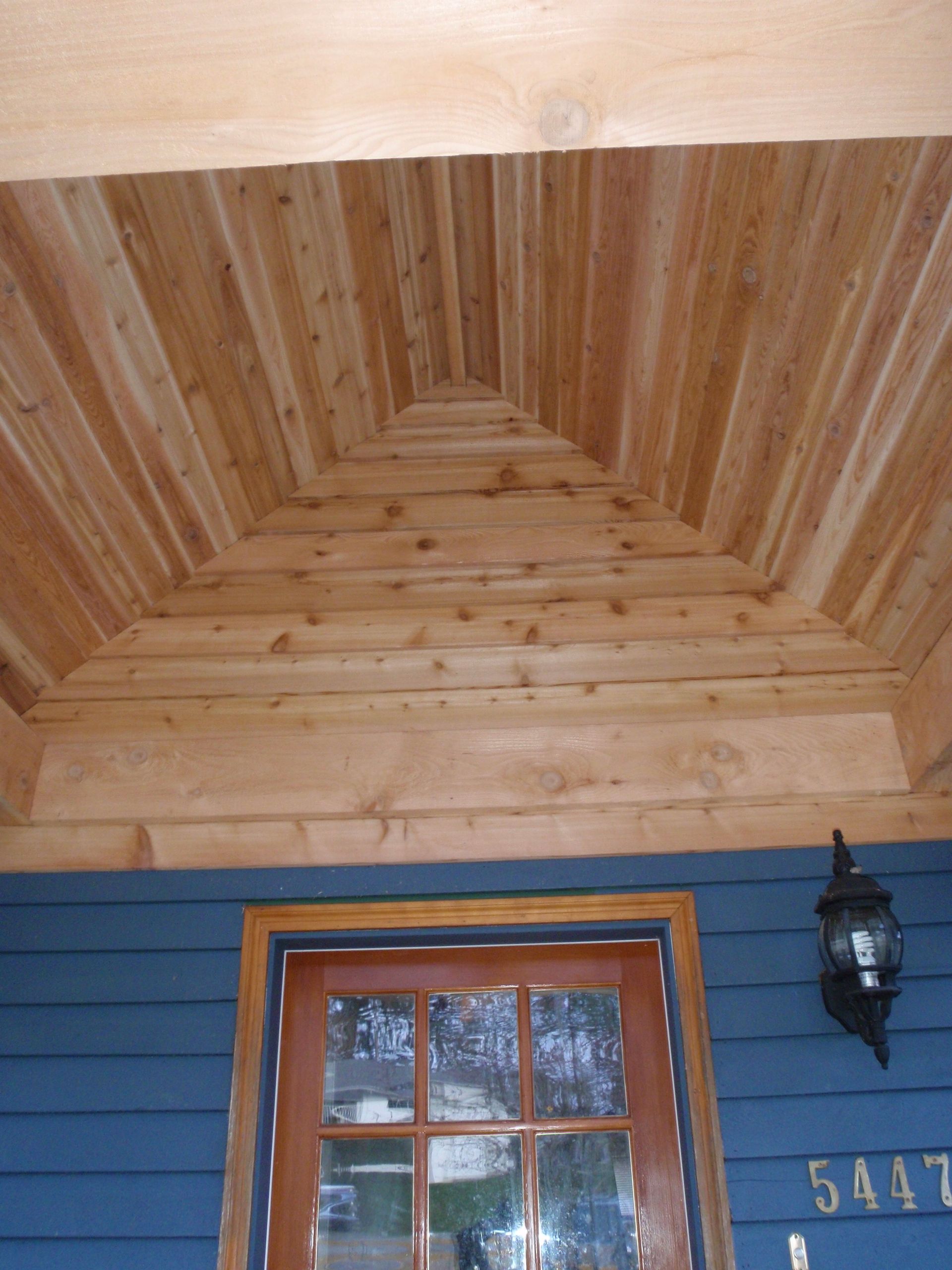 A blue house with a wooden door and a wooden ceiling