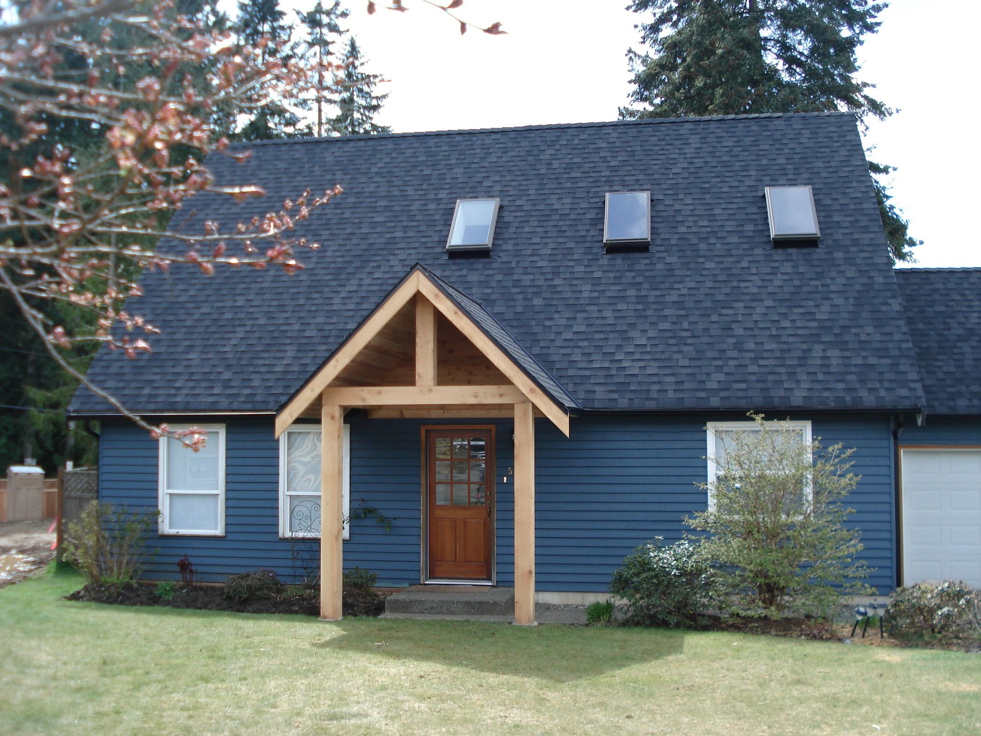 A blue house with a wooden porch and skylights on the roof