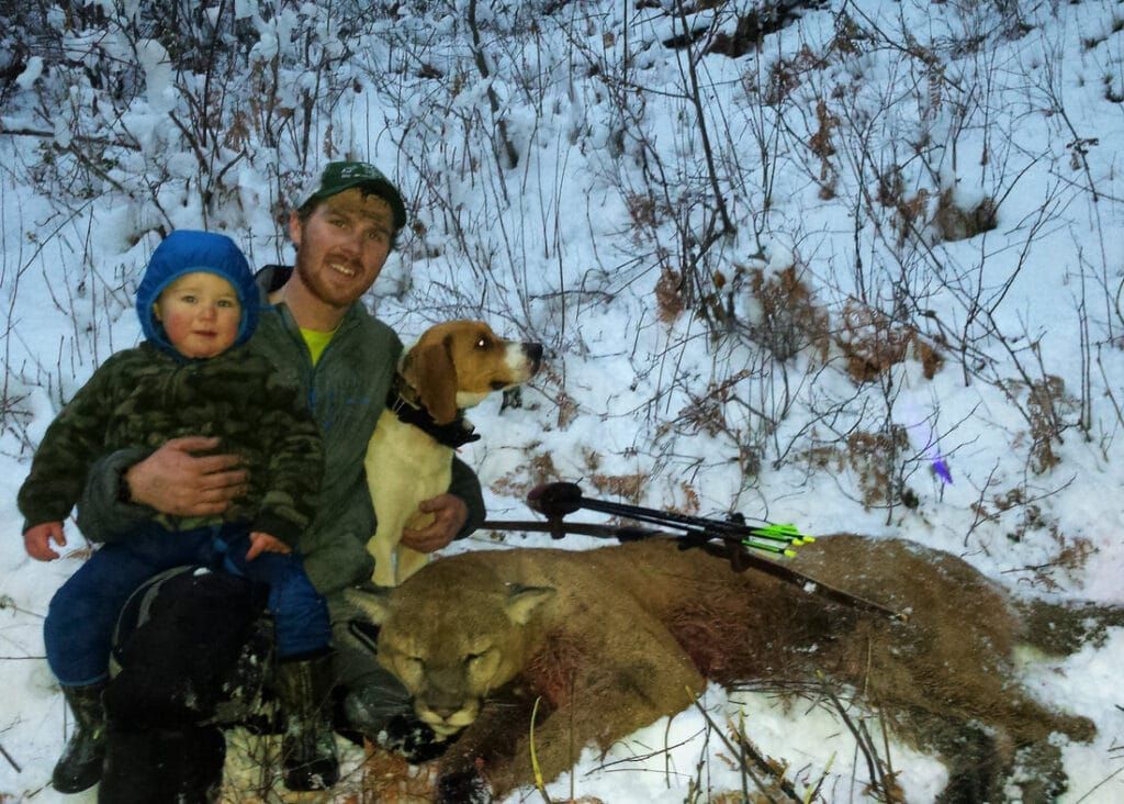 man holding child and dog next to mountain lion hunt