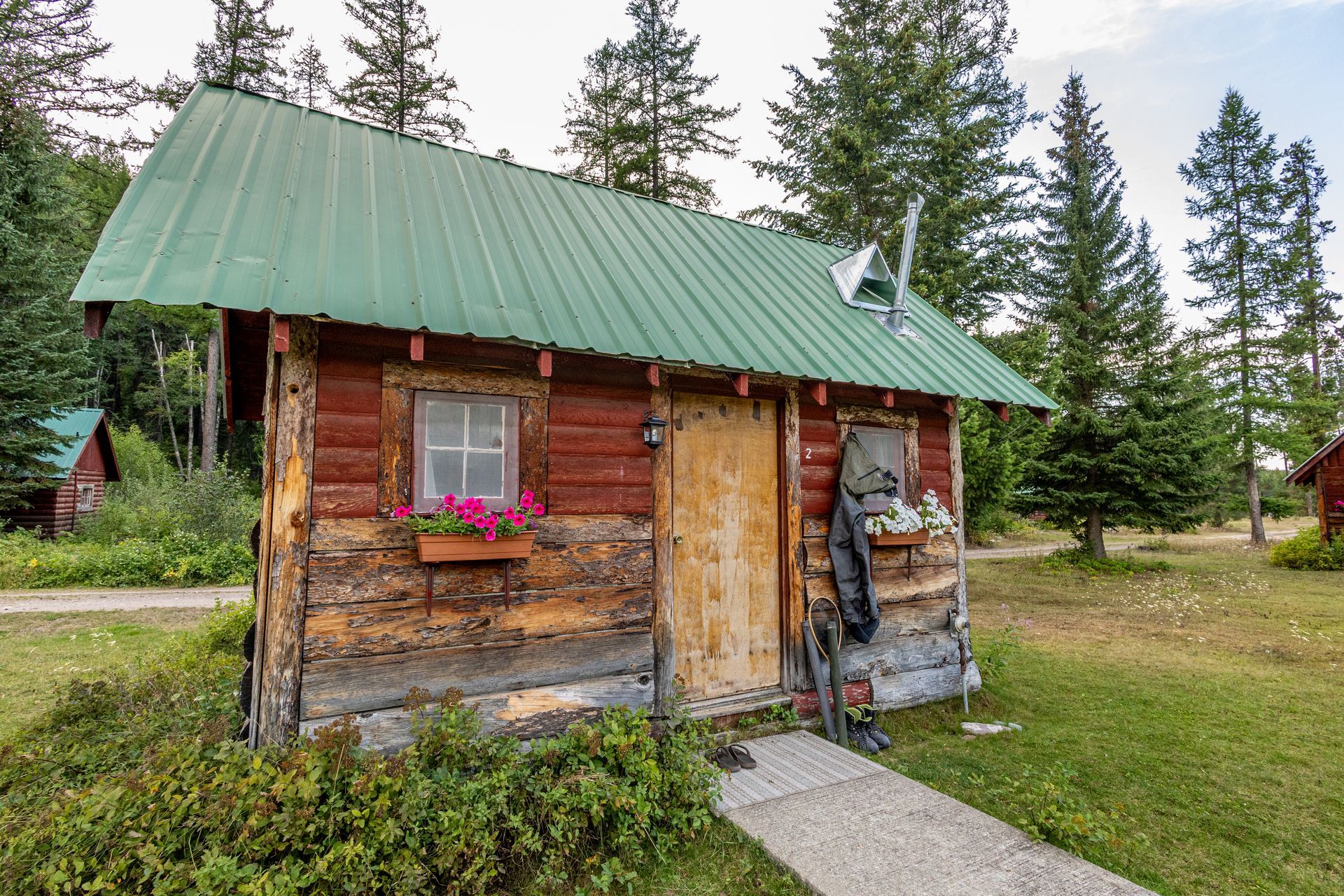 A person is holding a montana wilderness coffee mug in front of a cabin.