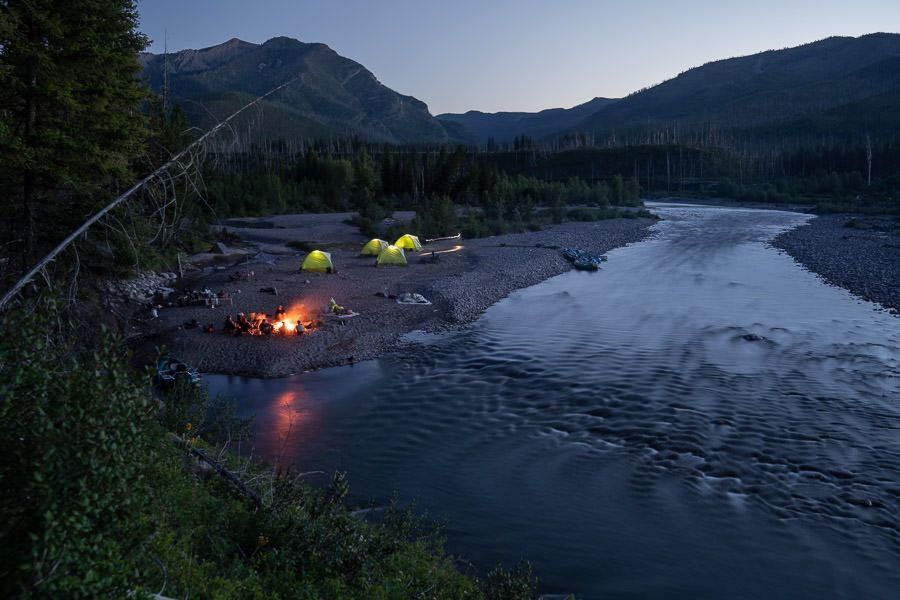 A group of tents are sitting on the shore of a river.