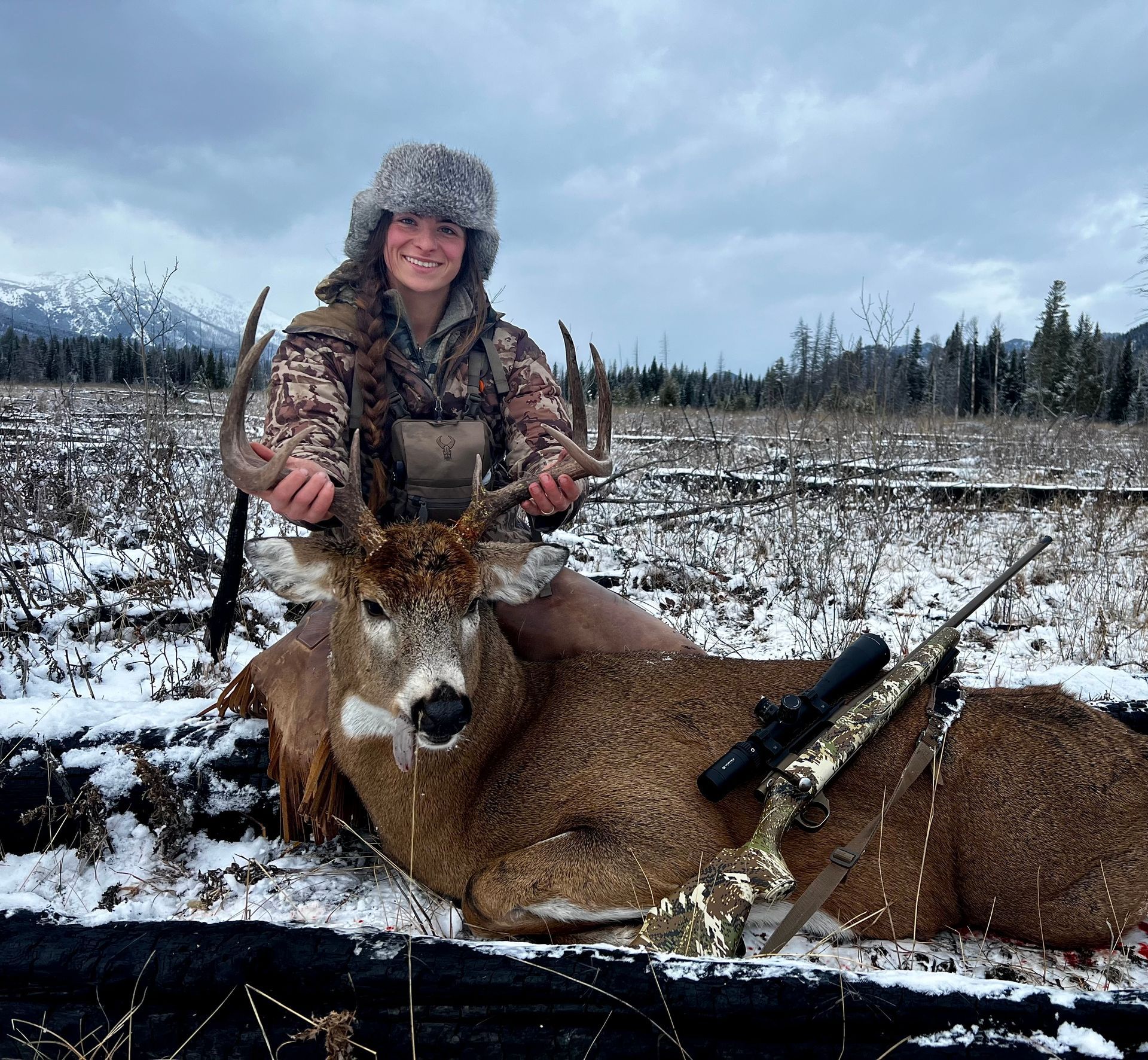 A row of rafts on the shore of a river with mountains in the background