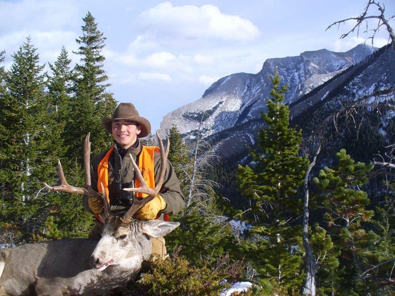 man holding antlers of deer in mountains