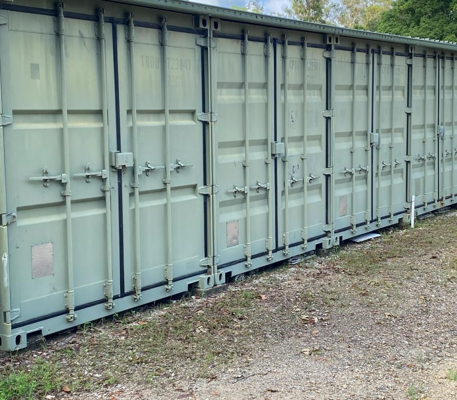 A Row Of Shipping Containers Are Lined Up In A Gravel Area — Byron Storage Services In Myocum, NSW