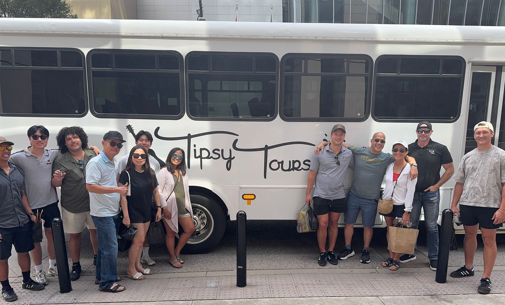 Group of people pose in front of a white bus,