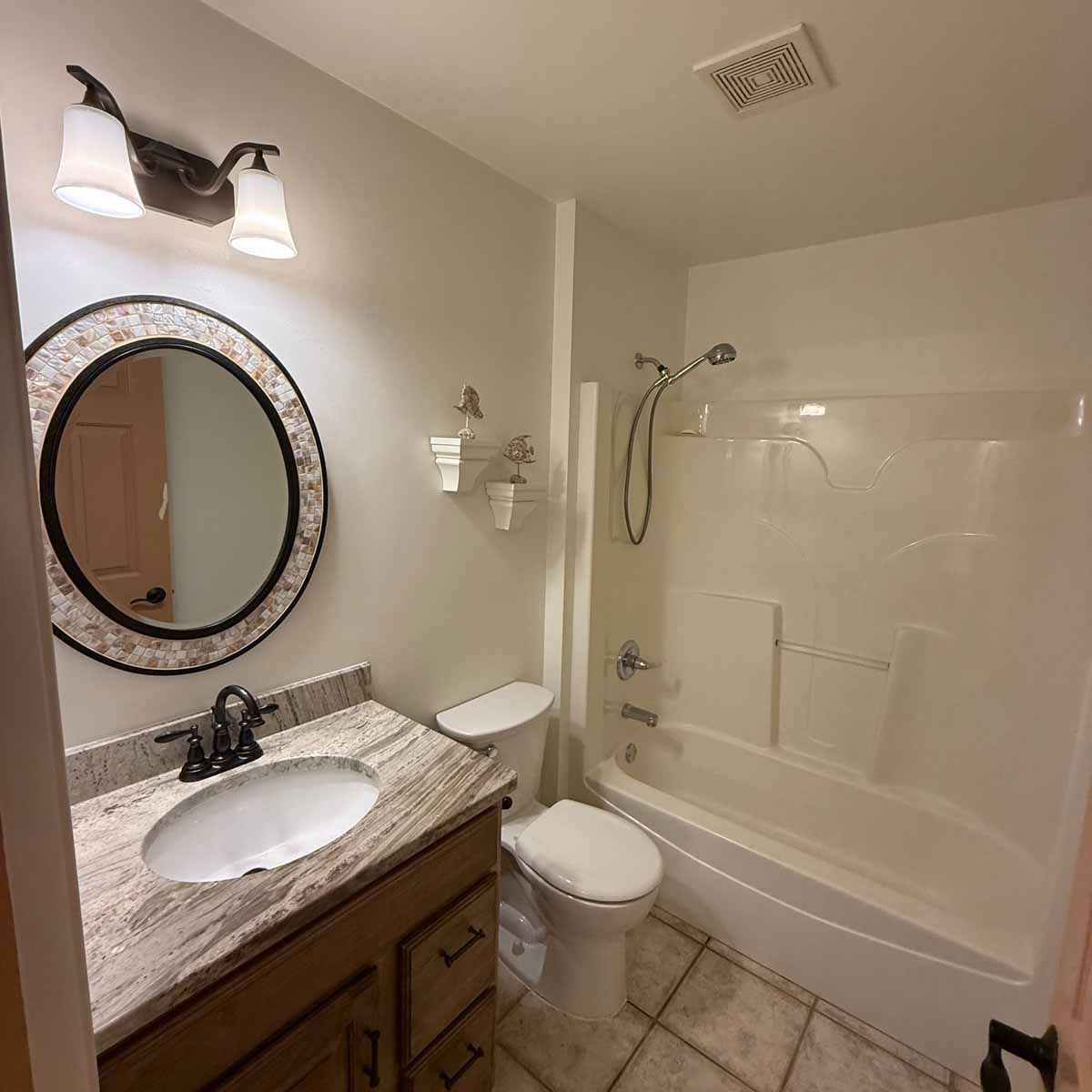 Bathroom with white walls, toilet, sink, and shower/tub.