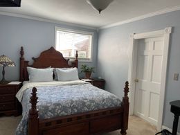 A bedroom with a bed , nightstand , lamp and window.