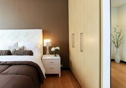 A bedroom with a bed , nightstand , lamp and window.
