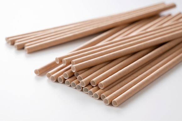 A pile of brown paper straws on a white surface