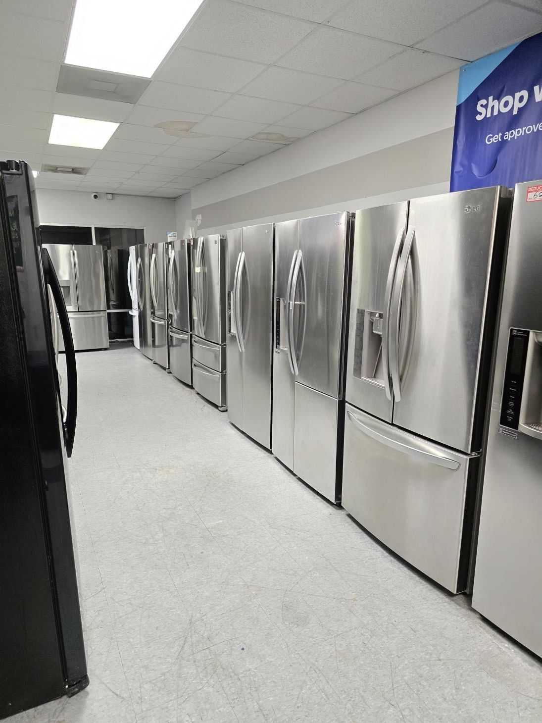 A kitchen with white cabinets , stainless steel appliances , a washer and dryer , and a refrigerator.