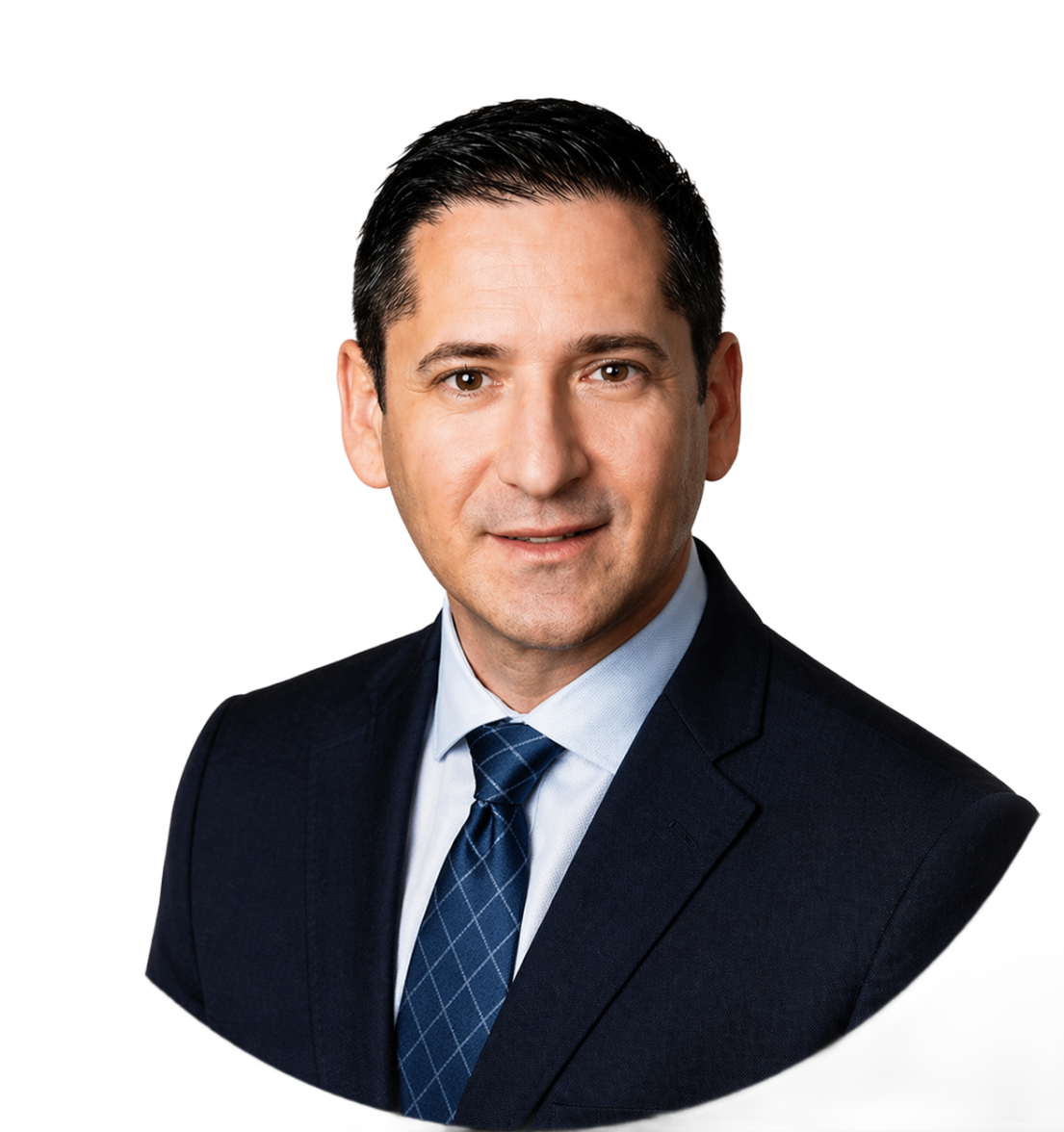 Headshot of Jim Metaxas in a dark suit and blue patterned tie against a plain light brown background.
