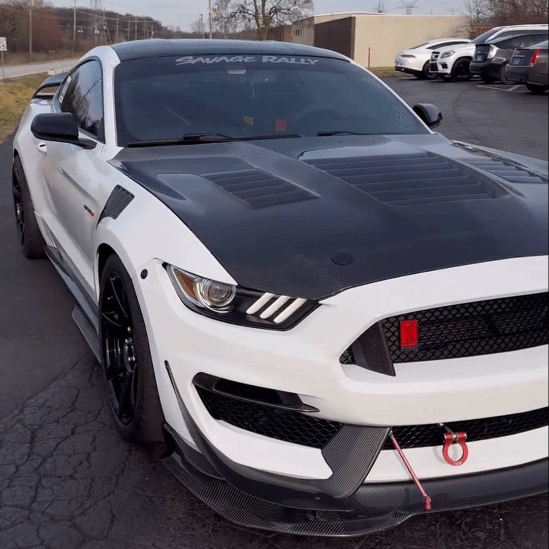 White and black modified Ford Mustang sports car with black rims, parked outside.