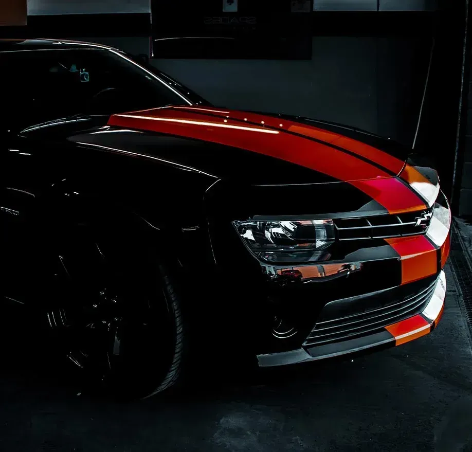 Black car with orange and red stripes on hood, front bumper.