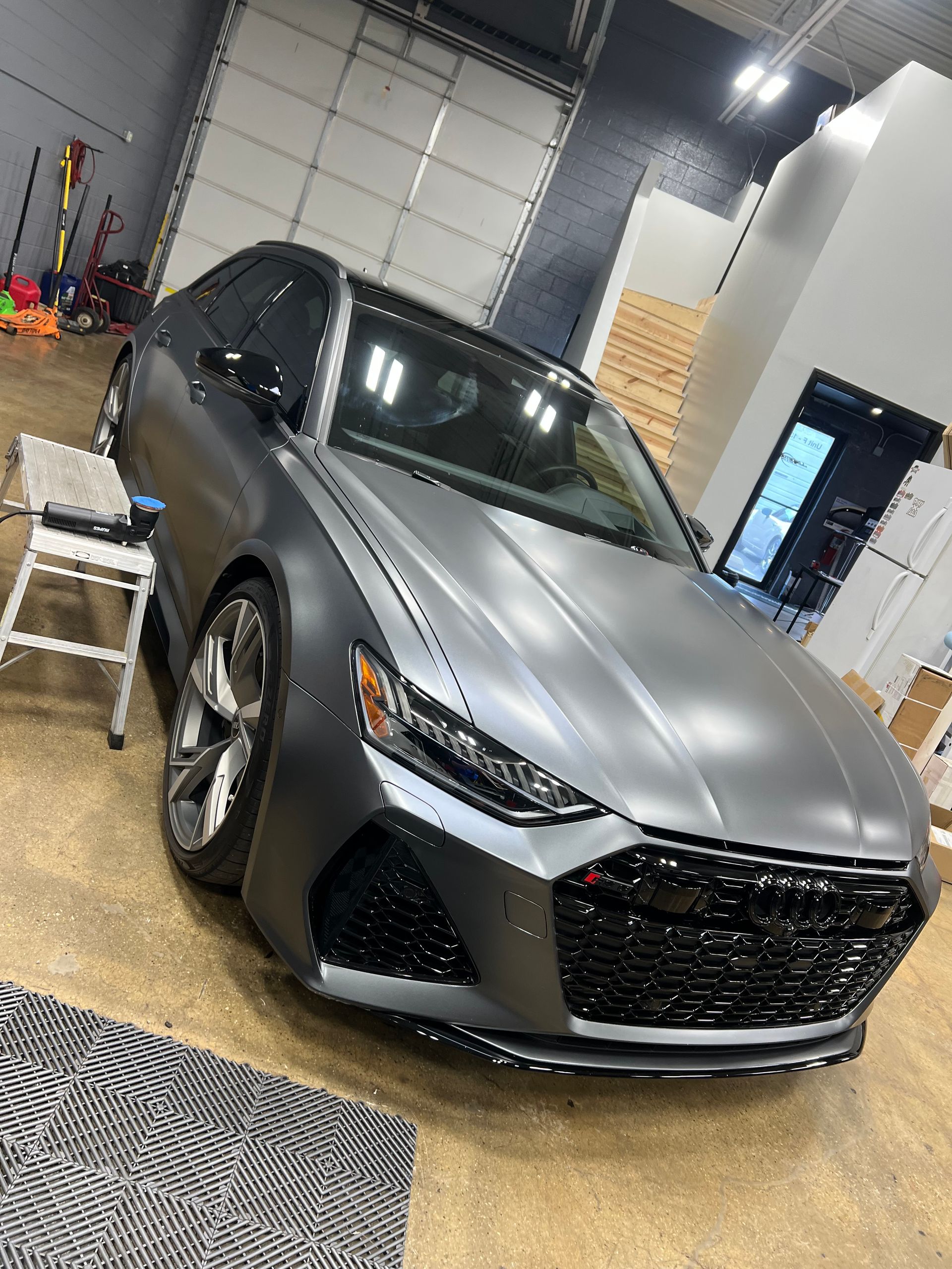Gray Audi RS6 sedan in a garage, black grille, matte finish.