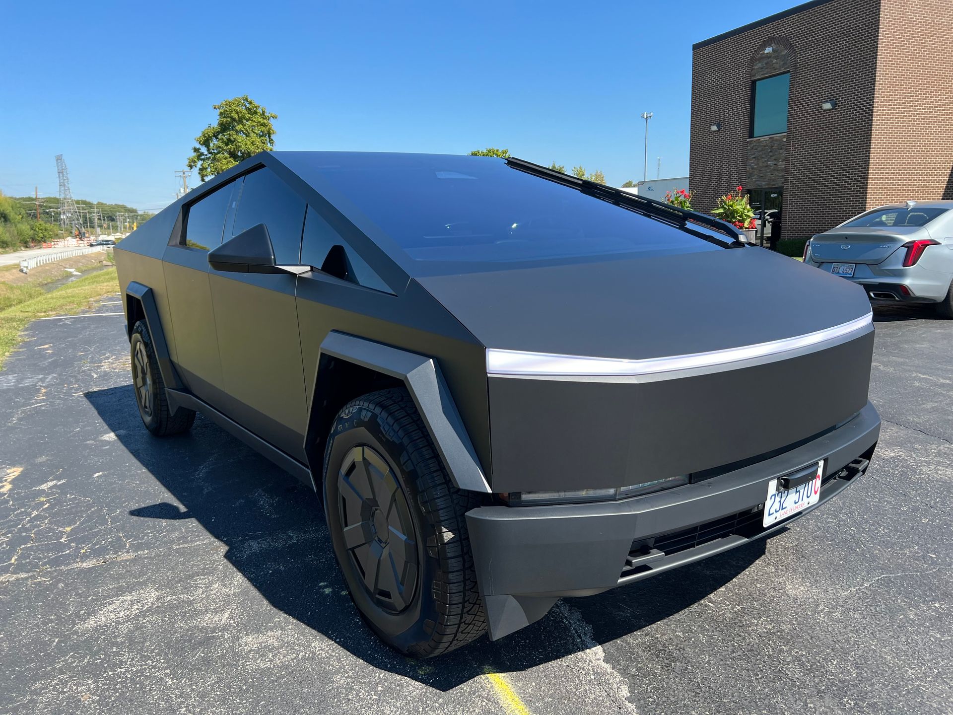 Matte gray Tesla Cybertruck parked outdoors near a building.