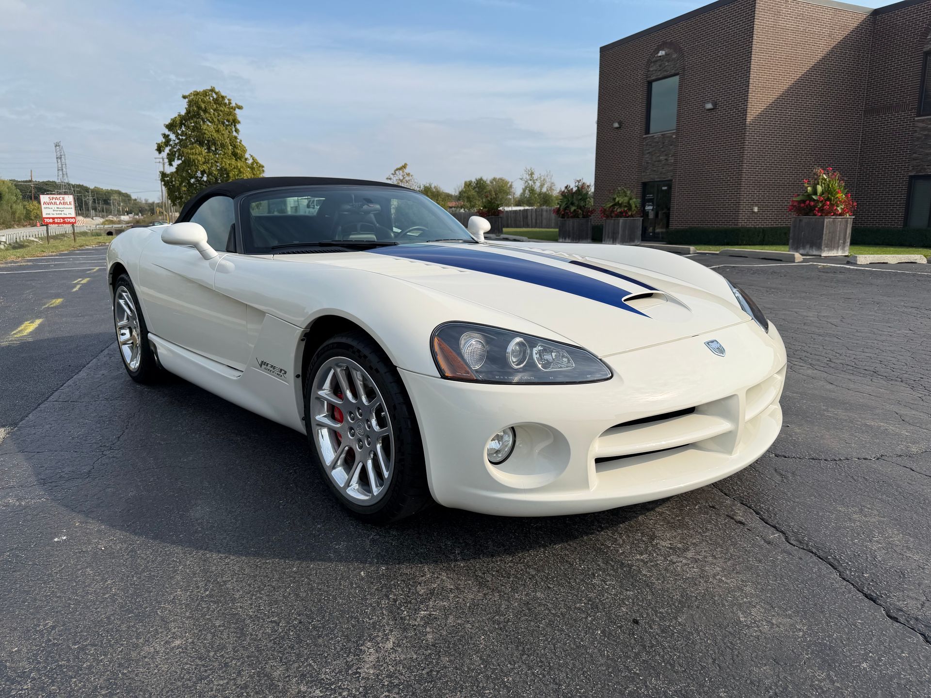 White Dodge Viper convertible with blue racing stripes, parked on asphalt.