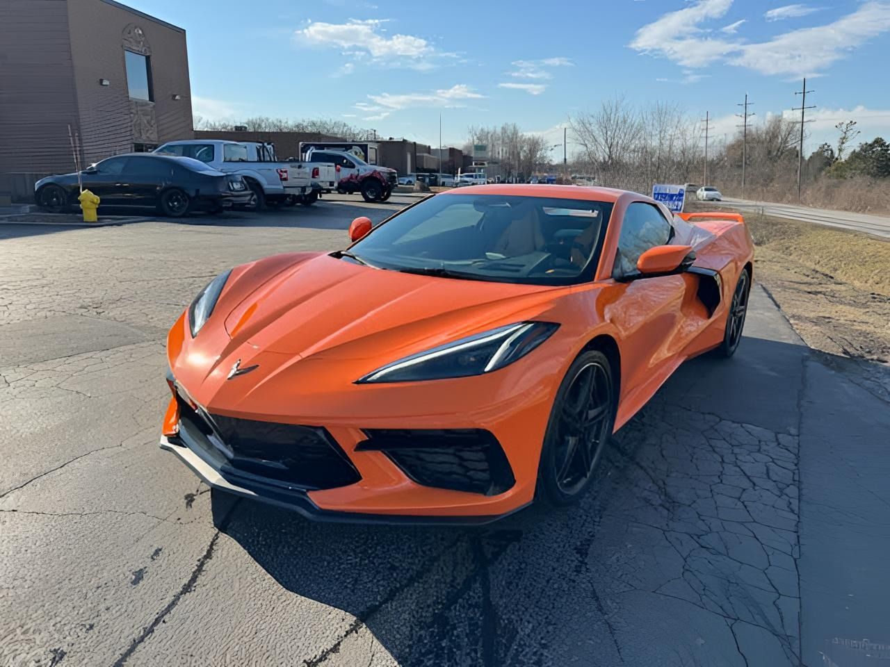 Orange Corvette sports car parked on pavement on a sunny day.