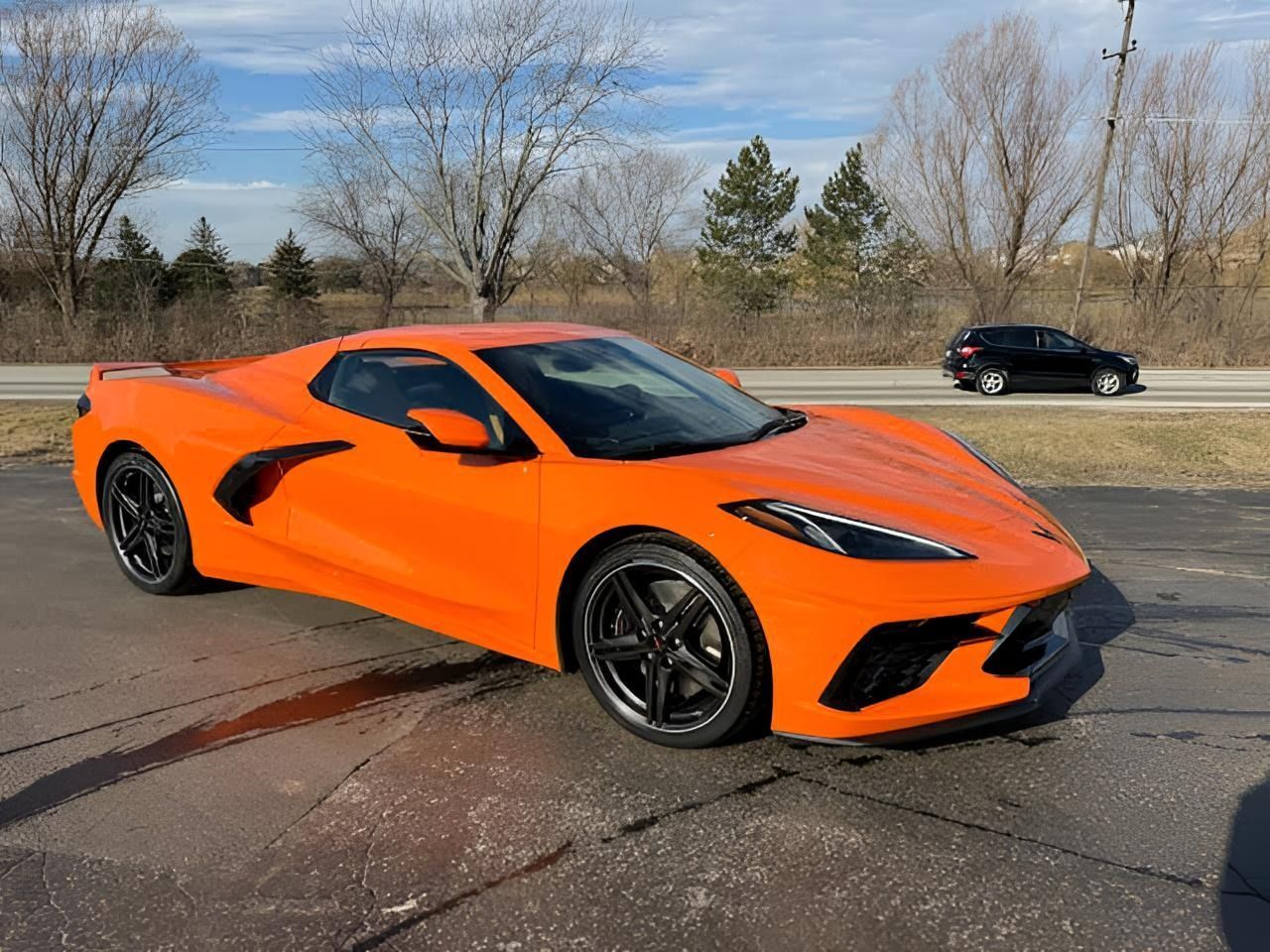 Bright orange Chevrolet Corvette sports car parked on pavement.