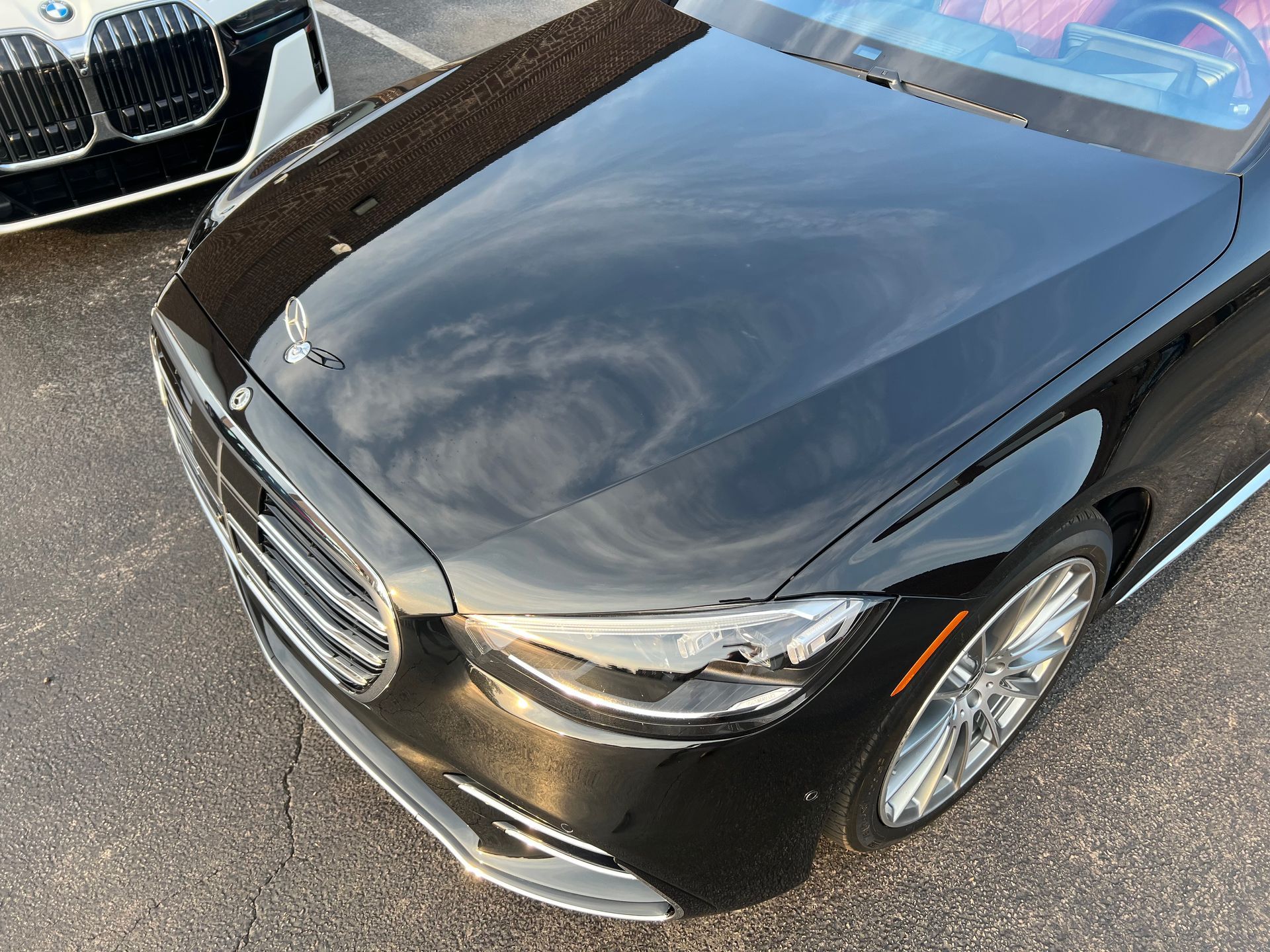 Black Mercedes-Benz convertible with silver rims, parked next to a white BMW. Outdoors.