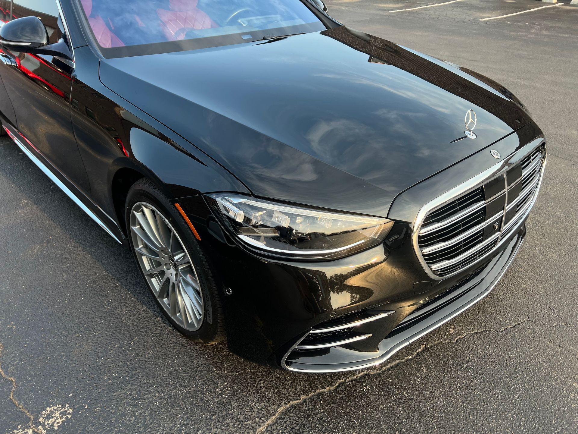 Black Mercedes-Benz sedan parked on asphalt. Shiny black finish, chrome accents, and large front grill.