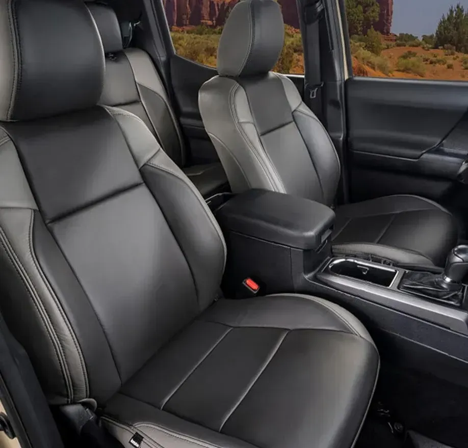 Black and gray leather interior of a car, including front seats, center console, and a glimpse of a desert landscape.