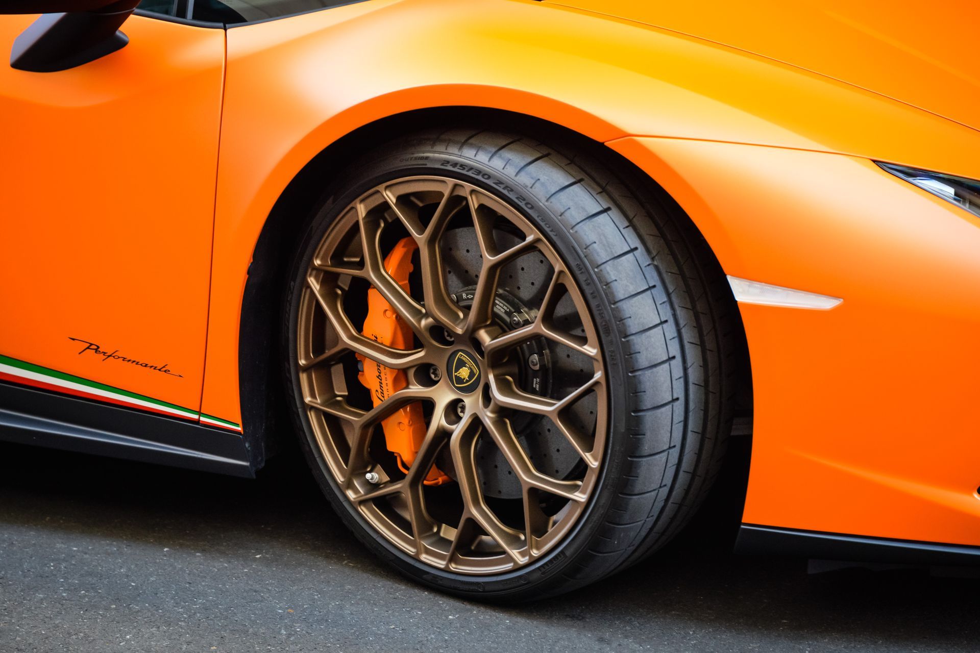 Underside of a vehicle, showing a black tire, suspension, red brake calipers, and a spare tire.