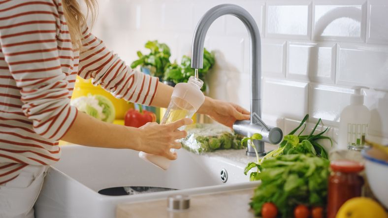 Woman Filling a Reusable Plastic Bottle