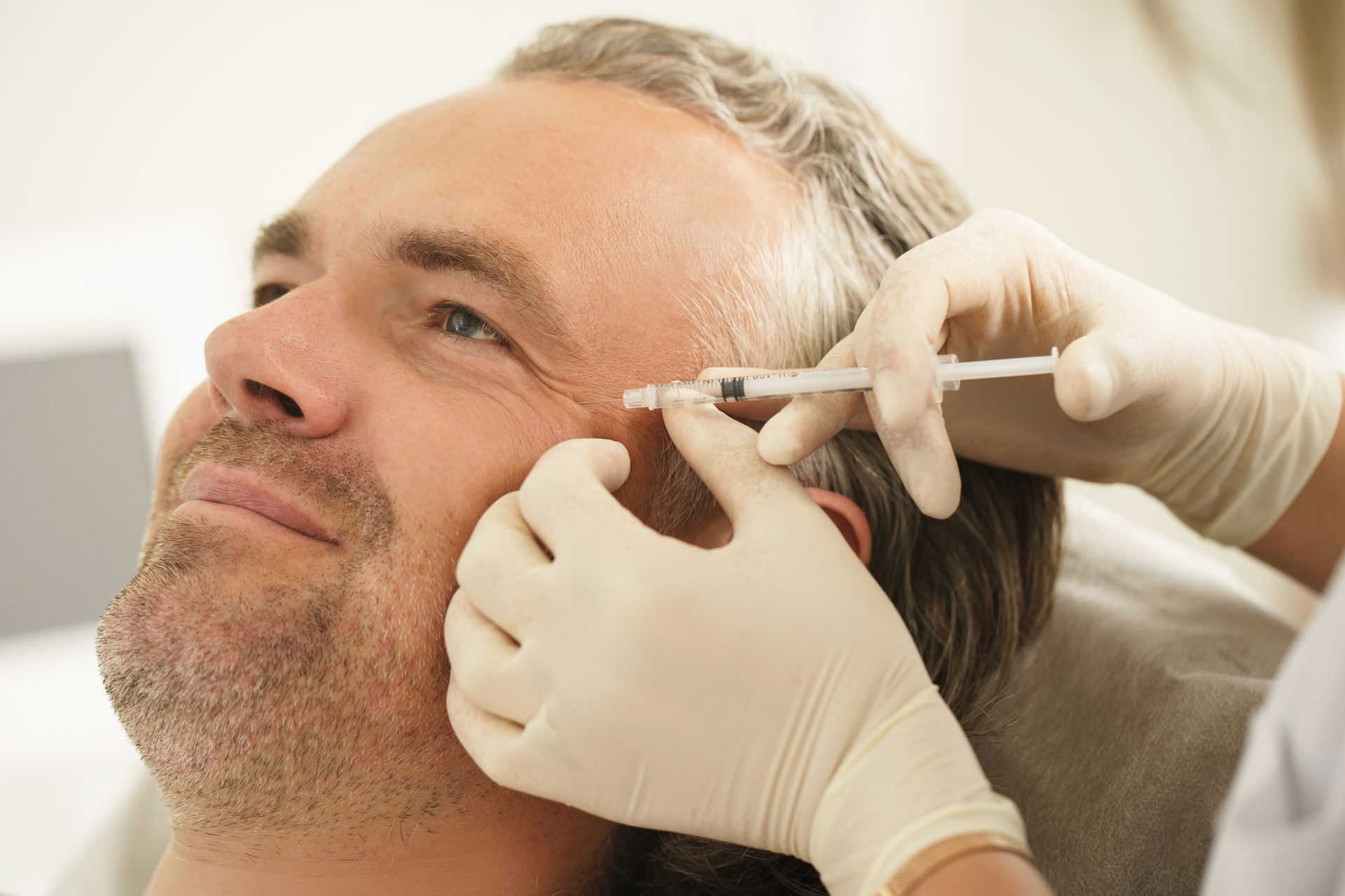 Ein Mann bekommt eine Botox-Injektion in die Stirn.