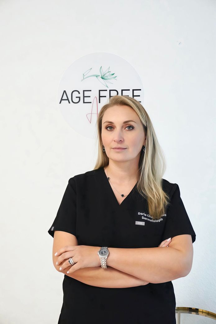 Eine Frau, die mit einer Uhr und einer Halskette an einer Wand lehnt