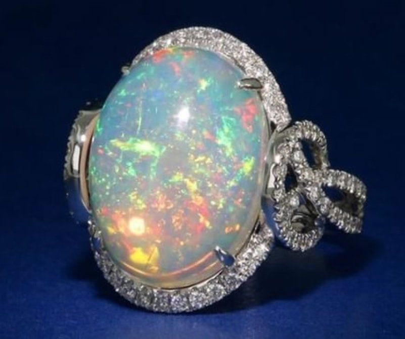 A ring with an opal and diamonds on a blue surface
