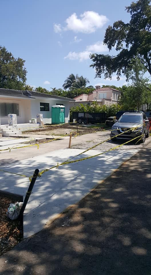A car is parked on the side of the road in front of a house.