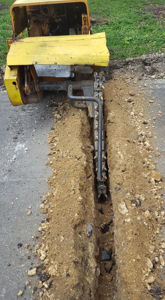 A yellow tractor is digging a trench in the ground.
