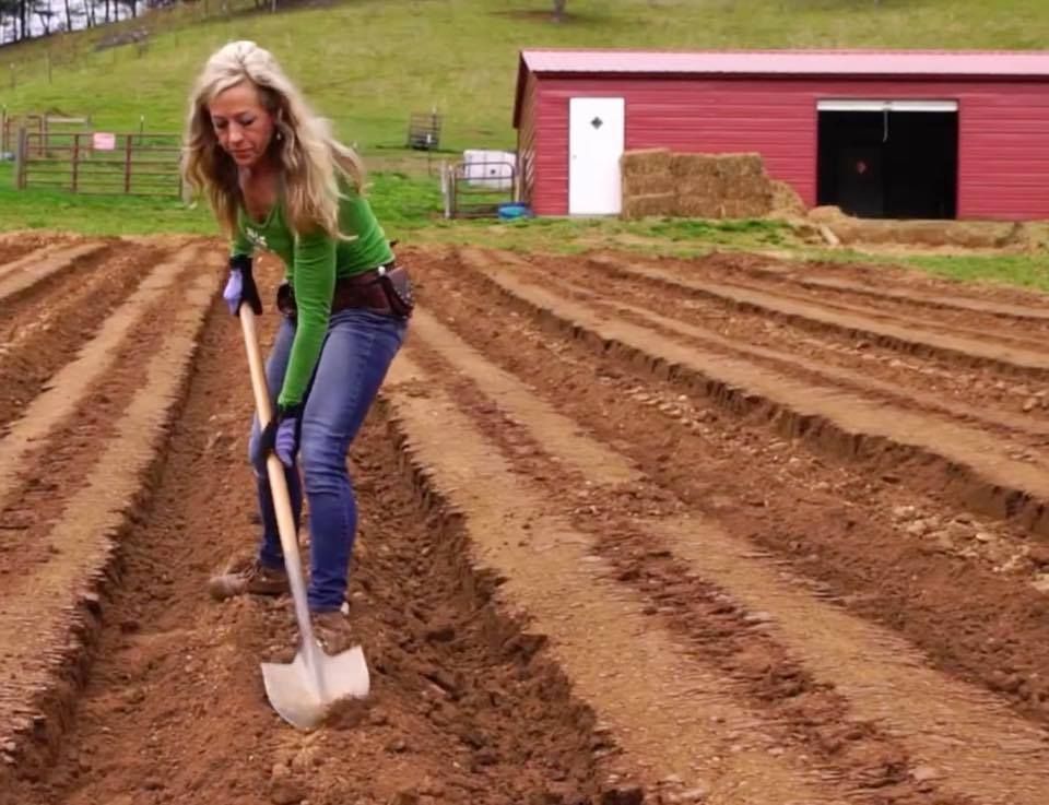 CEO and Founder of Franny's Farmacy Franny Tacy using a shovel to till soil on the farm to prepare to grow hemp.