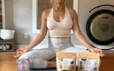 Franny Tacy meditating in a yoga pose, wearing a halter top and leggings. Two product bags and a gong are in the background.
