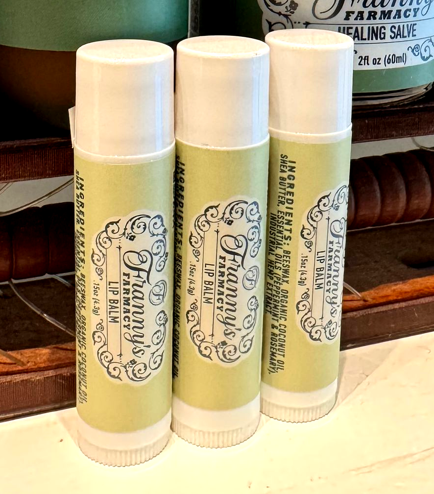 Three lip balm tubes with white caps and a pale green Franny's Farmacy label