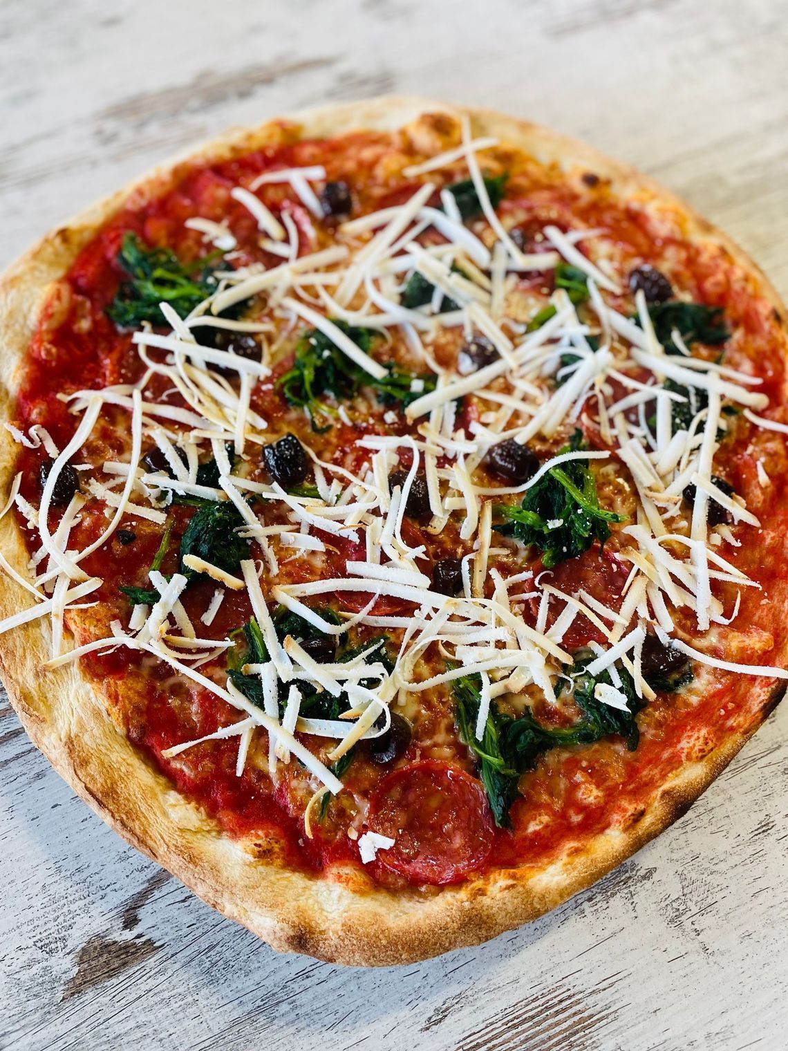 una persona tiene in mano una pizza con prosciutto e formaggio