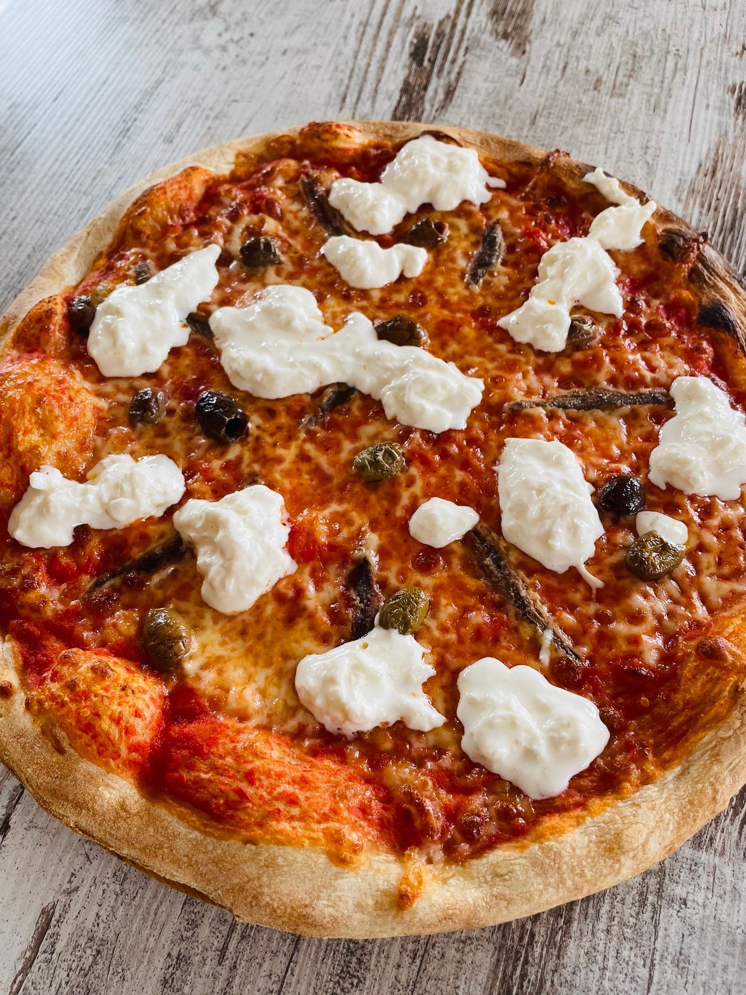 una pizza con tonno e cipolle su un tagliere di legno