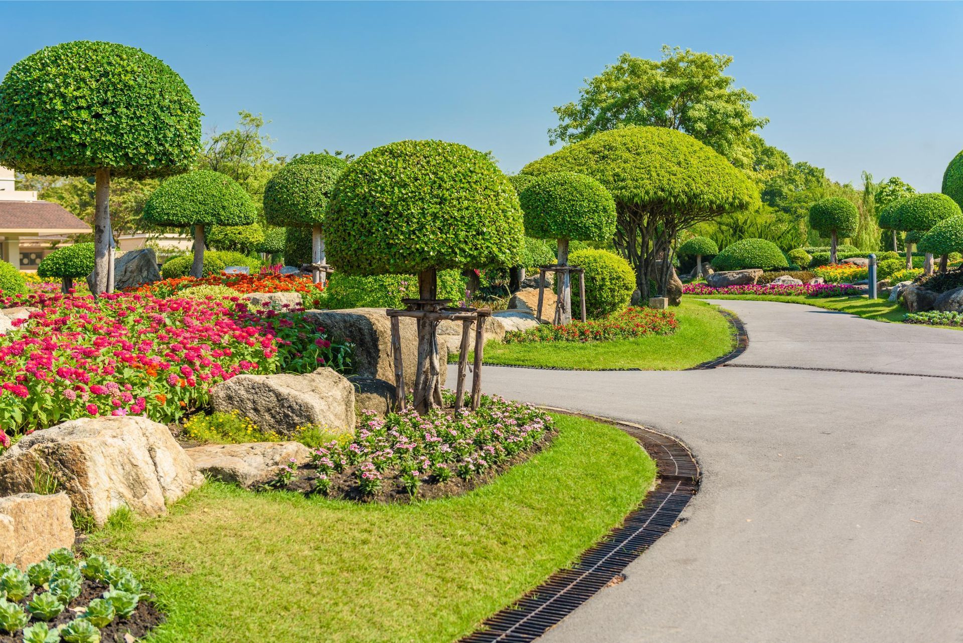 Manicured garden with round-shaped trees and a winding paved path.