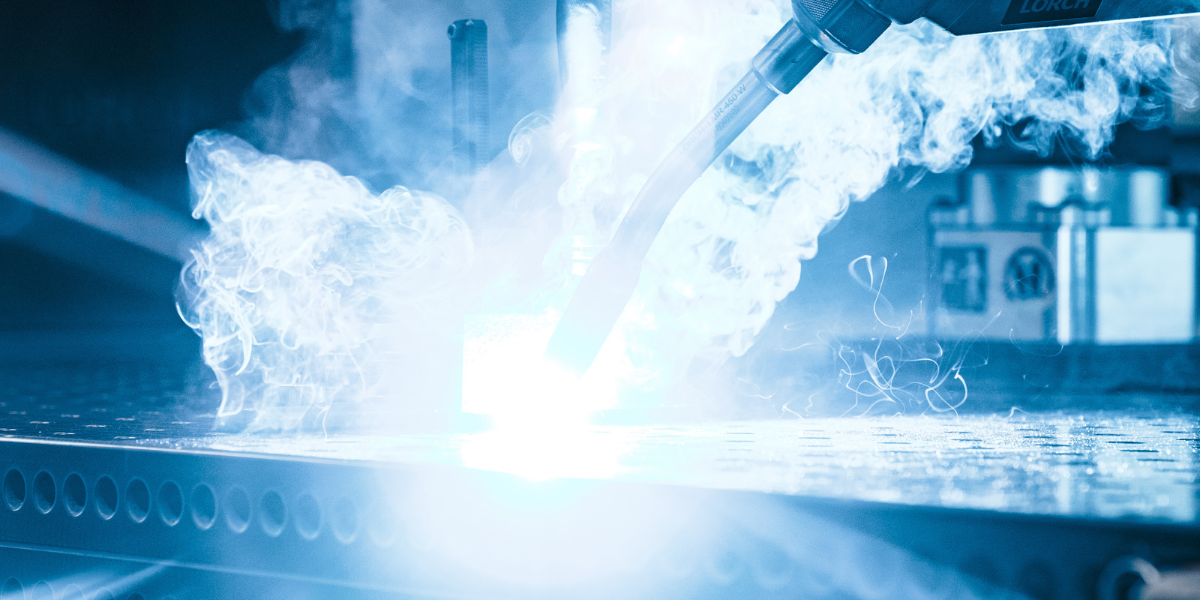 Ein Laserschneider in Aktion, mit hellblauem Licht und Funken.