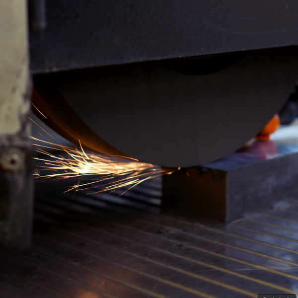 Schleifscheibe in Aktion, Funken sprühen, ein Metallblock wird in einer Werkstatt geformt.