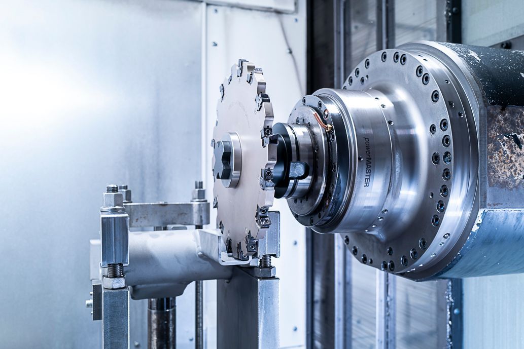 Eine CNC-Maschine schneidet in einer Fabrikumgebung ein kreisförmiges Metallteil mit mehreren Zähnen.