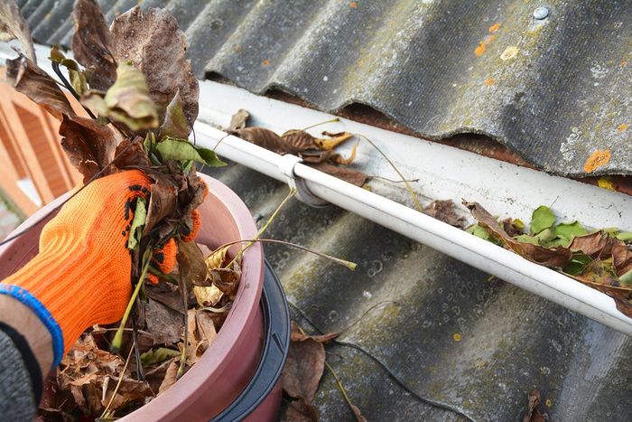 someone removing leaves on gutter